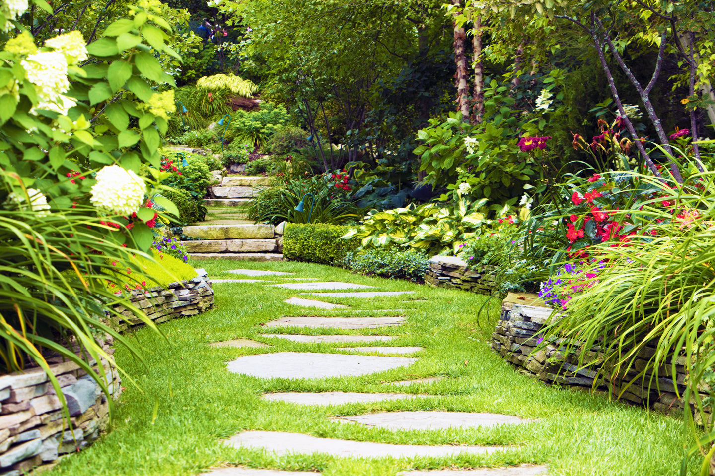 A flagstone path meanders into a private cottage garden on Mackinac Island, beckoning viewers to take time to enjoy the nature around them. The tranquil setting evokes a sense of calm.