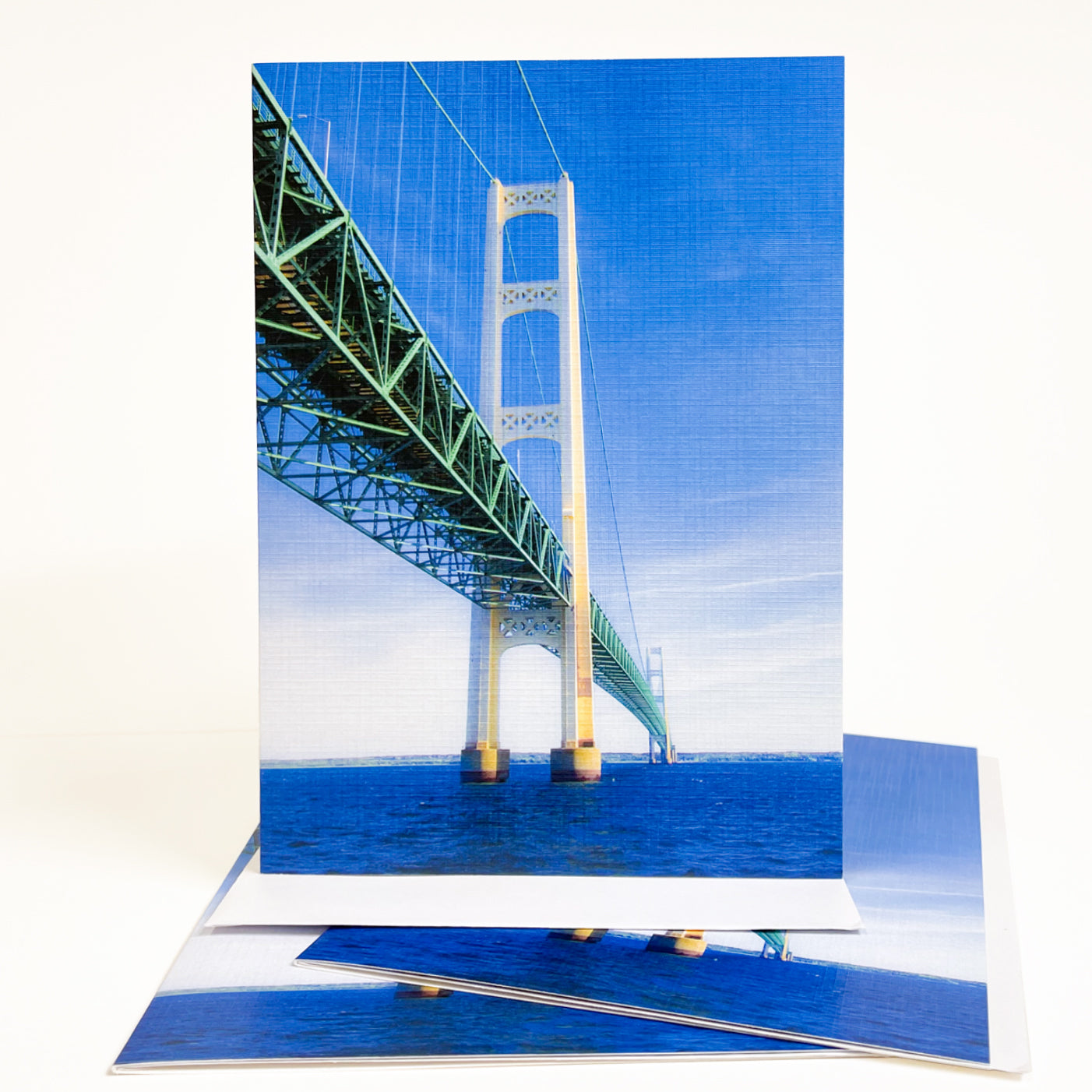 Blank greeting card featuring a photograph of the Mackinac Bridge by Michigan artist Jennifer Wohletz of Mackinac Memories. Looking up at the Mackinac Bridge from the water reveals the mammoth size of the bridge's towers that anchor it to the bottom of the lake. Open the card to discover an interesting perspective of the bridge's strong foundation. Photos by Jennifer Wohletz. The card is meant to be shared or displayed as a work of art.