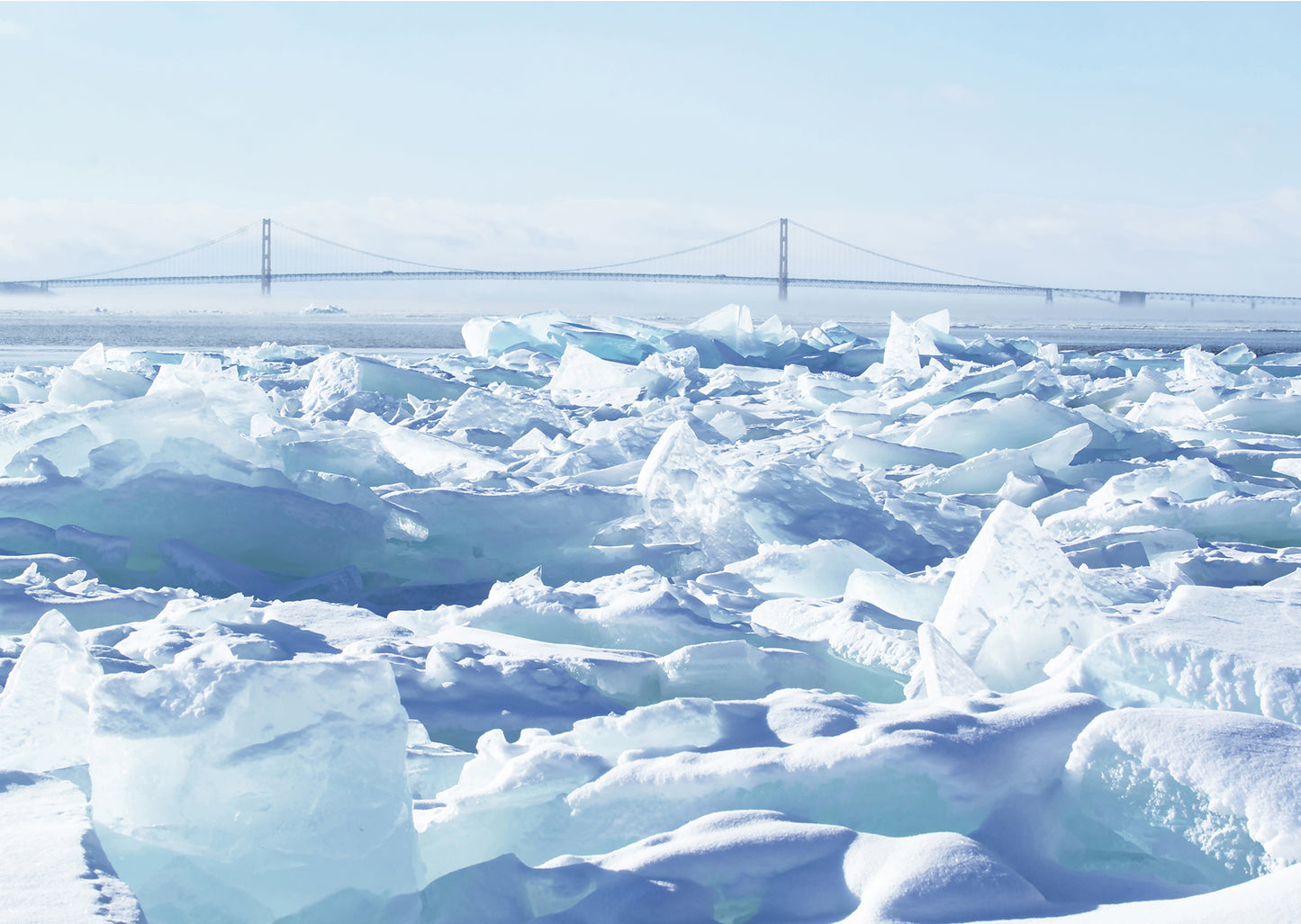 The Mackinac Bridge stands strong behind a veil of mist and wall of blue ice in this photo by Jennifer Wohletz of Mackinac Memories.