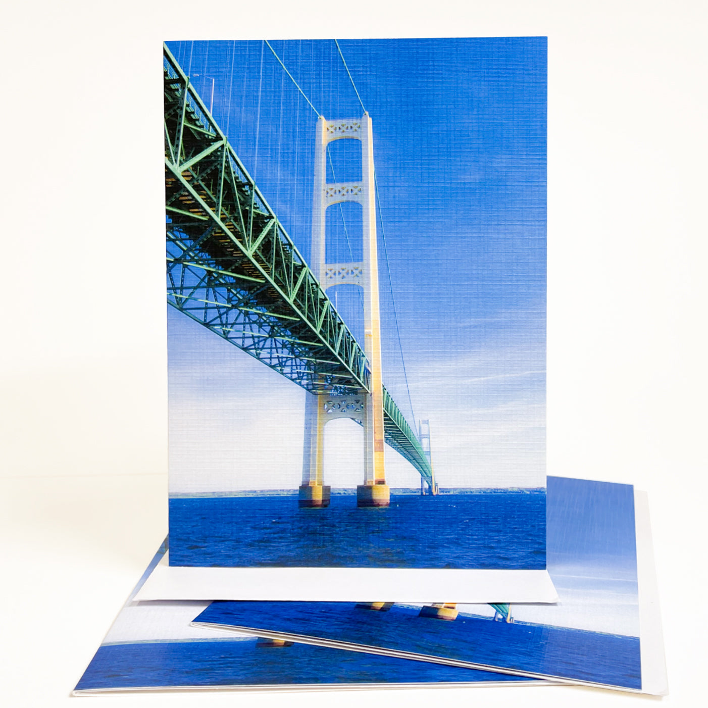 Blank greeting card featuring a photograph of the Mackinac Bridge by Michigan artist Jennifer Wohletz of Mackinac Memories.  Looking up at the Mackinac Bridge from the water reveals the mammoth size of the bridge's towers that anchor it to the bottom of the lake. Open the card to discover an interesting perspective of the bridge's strong foundation. Photos by Jennifer Wohletz.  The card is meant to be shared or displayed as a work of art.  